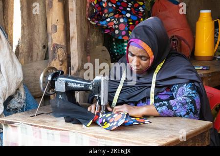 Mtowambu, Tansania - 12.. Oktober 2022: Eine Näherin bei der Arbeit auf einem Marktplatz in der kleinen Stadt Mtowanbu, Tansania. Stockfoto