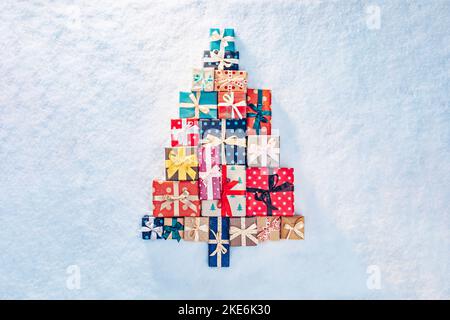 Viele Geschenke in Form eines Weihnachtsbaums im Schnee Stockfoto