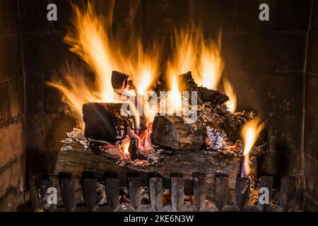 Beleuchteter Holzkamin im Wohnzimmer im alten, renovierten Haus im kanadischen Cottage-Stil aus dem Jahr 1840. Stockfoto