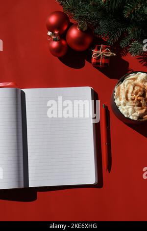 Rote Weihnachtskomposition mit heißer Schokolade und Notizbuch für Wunschliste Stockfoto