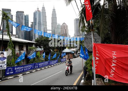 Kuala Lumpur, Malaysia. 10.. November 2022. Ein Motorradfahrer fährt während der Parlamentswahlen in Kuala Lumpur an den politischen Parteiflaggen des Front National oder der Barisan Nasional (Blaue Flagge) - der derzeitigen Übergangsregierung und Allianz der Hoffnung oder Pakatan Harapan (Rote Flagge) - vorbei. (Bild: © Wong Fok Loy/SOPA Images via ZUMA Press Wire) Stockfoto