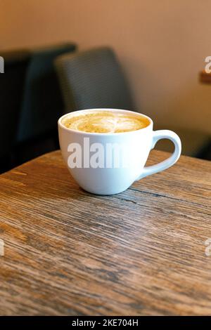 Eine Tasse heißen Cappuccino-Kaffee auf einem rustikalen Tisch. Café Stockfoto