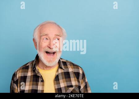 Foto von beeindruckt lustig pensionierten Mann tragen kariertes Hemd offenen Mund suchen leeren Raum isoliert blauen Hintergrund Stockfoto