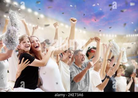 Fußballfan im Stadion in schwarz-weißem Hemd. Fröhliche Fans auf dem Fußballfeld, die das siegreiche Mannschaftsspiel beobachten. Eine Gruppe von Anhängern jubelte aufgeregt. Stockfoto