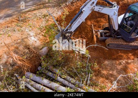 Bei Verwendung Traktoren Skid Steers wurden Landschaftsarbeiten auf Aushub von Wurzeln aus dem Boden für die geplante Unterteilung durchgeführt Stockfoto