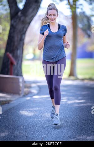 Junge Frau in Pink, Grau und Lavendel, die im Downtown San Jose Park arbeitet Stockfoto