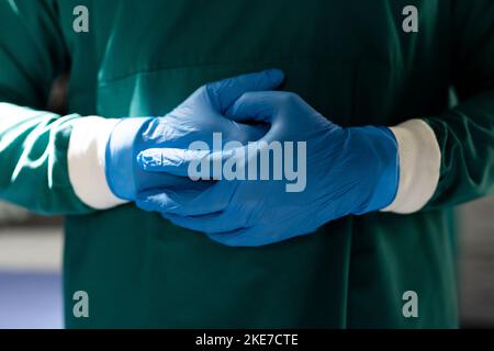 Die Mitte des Chirurgen in blauen Handschuhen und grünem Kleid im Operationssaal Stockfoto