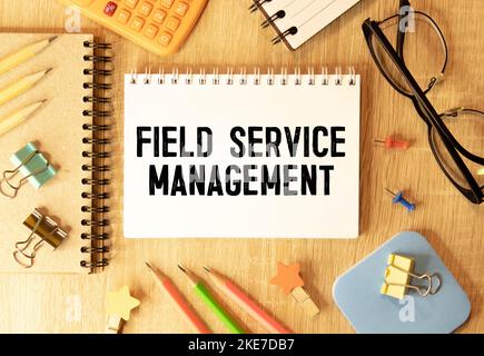 Auf hellblauem Hintergrund helle Holzblöcke und Würfel mit dem Text FSM Field Service Management. Stockfoto