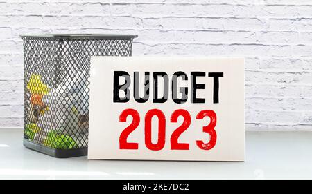 Notizblock mit Text BUDGET 2023, Brille, Büroklammern, weißem Taschenrechner und Stift auf Desktop, Draufsicht Stockfoto