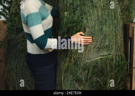 Eine Frau, die einen Weihnachtsbaum kauft, der in ein Netz gehüllt ist Stockfoto