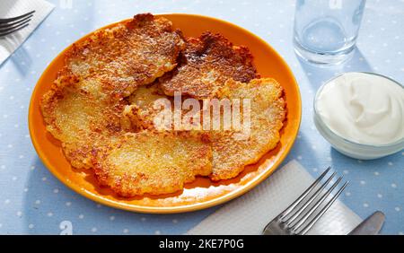 Weißrussische Kartoffelpfannkuchen draniki mit saurer Rahm auf dem Teller Stockfoto