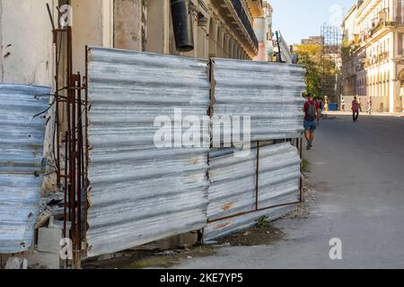 Ein alter verfallenen Metallzaun schützt ein Gebäude, das in Gefahr ist einzustürzen. Stockfoto