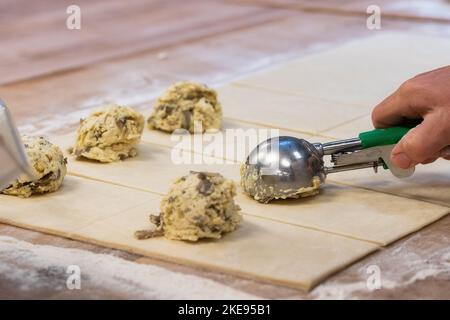 Ein Bäcker schaufeln eine herzhafte Füllung auf den Teig Stockfoto