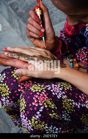 Nepalesische Mädchen Künstler verwenden Henna Tinte schreiben Zeichnung malen mehndi Henna Tattoo als Körper Kunst Muster auf der Hand von Reisenden thai Frauen reisen Besuch in thamel ol Stockfoto