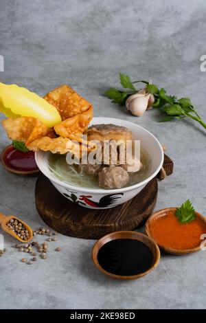 Bakso oder indonesischer Fleischbällchen mit Brühsuppe, Tofu, Nudel und frittiertem Wonton oder Knödel auf einer weißen Schüssel Stockfoto