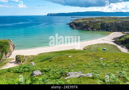 Schottischer Campingplatz, atemberaubender Sand, ruhiges, azurblaues atlantisches Meer, sonniger Sommermorgen, mit Gras bewachsen, unter dem Beinn Ceannabeinne Berg, wunderschöne Stockfoto