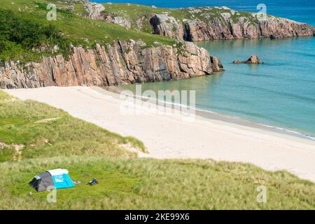Schottischer Campingplatz, atemberaubender Sand, ruhiges, azurblaues atlantisches Meer, sonniger Sommermorgen, mit Gras bewachsen, unter dem Beinn Ceannabeinne Berg, wunderschöne Stockfoto
