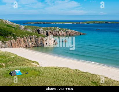Schottischer Campingplatz, atemberaubender Sand, ruhiges, azurblaues atlantisches Meer, sonniger Sommermorgen, mit Gras bewachsen, unter dem Beinn Ceannabeinne Berg, wunderschöne Stockfoto