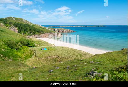 Schottischer Campingplatz, atemberaubender Sand, ruhiges, azurblaues atlantisches Meer, sonniger Sommermorgen, mit Gras bewachsen, unter dem Beinn Ceannabeinne Berg, wunderschöne Stockfoto