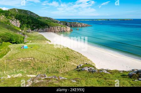 Schottischer Campingplatz, atemberaubender Sand, ruhiges, azurblaues atlantisches Meer, sonniger Sommermorgen, mit Gras bewachsen, unter dem Beinn Ceannabeinne Berg, wunderschöne Stockfoto