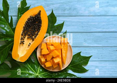 Papaya-Früchte auf blauem Hintergrund, frisch reife Papaya-Scheibe in halbtropische Früchte mit Papaya-Samen und Blattblättern vom Papaya-Baum geschnitten - Draufsicht Stockfoto