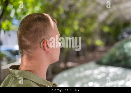 Nahaufnahme eines Hörgeräts am Ohr eines Mannes. Stockfoto