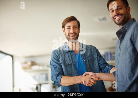 Gemeinsam machen wir es möglich. Porträt von zwei Geschäftsleuten, die sich im Büro die Hände schütteln. Stockfoto