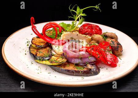 Gebackenes Gemüse mit Pilzen und Käse auf einem Teller Stockfoto