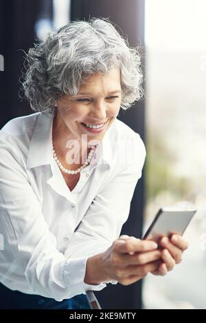 Lesen durch einen positiven Text von einem Kunden. Eine reife Geschäftsfrau SMS auf einem Handy. Stockfoto