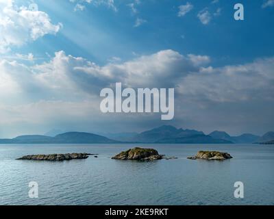 Die winzigen Inseln Eilean Ruairidh in Loch Eishort mit den Black Cuillin Bergen in der Ferne aus Sicht von Tokavaig, Isle of Skye, Schottland, Großbritannien Stockfoto