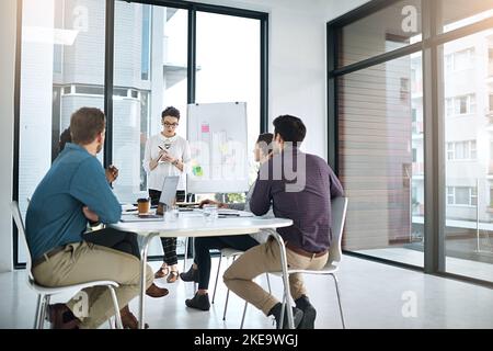 Ich nehme Ihre Vorschläge zur weiteren Überprüfung zur Kenntnis... eine Geschäftsfrau, die ihren Kollegen in einem modernen Büro eine Präsentation gibt. Stockfoto