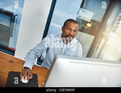 HES widmet sich der Deadline. Ein Geschäftsmann arbeitet an seinem Computer im Büro. Stockfoto