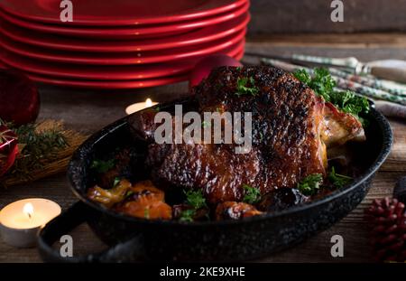 Weihnachtsbraten auf Holztisch mit Teelampen. Geröstete putenschenkel Stockfoto