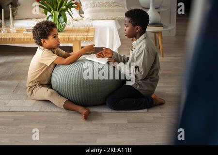 Jungs sitzen auf dem Boden und spielen zu Hause Stockfoto