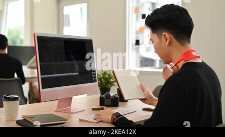 Junger männlicher Videoeditor, der mit Filmmaterial und Ton in einem modernen Kreativbüro arbeitet Stockfoto