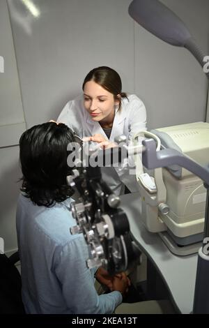 Augenärztin testet das Sehvermögen des Patienten mit speziellen optischen Geräten in der Klinik Stockfoto