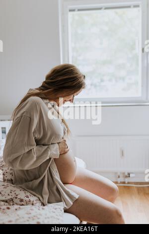 Schwangere Frau sitzen im Bett Stockfoto
