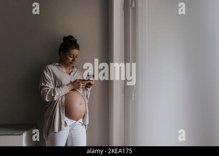 Schwangere Frau mit Handy Stockfoto