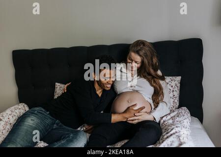 Schwangere paar auf Bett liegend Stockfoto