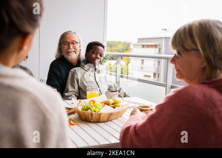 Familie sitzt am Tisch auf dem Balkon Stockfoto