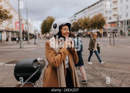 Lächelnde Frau, die den Helm aufsetzt Stockfoto