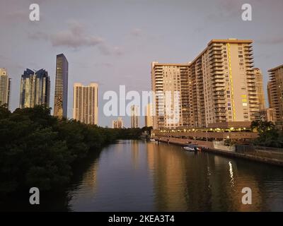 Sunny Isles, USA - 22. März 2021: Hochhäuser und grüne Bäume entlang des Flusses am blauen Himmel Stockfoto