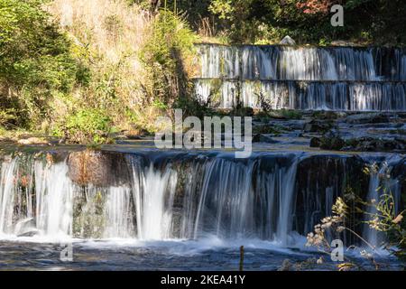 Ein wunderschöner Wasserfall, umgeben von Pflanzen und Bäumen an einem sonnigen Tag in Pec pod Snezkou Stadt Stockfoto