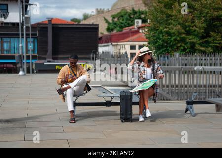 Männliche und weibliche Touristen sitzen auf einer Bank. Eine Pause nach dem ganzen Tag Stockfoto