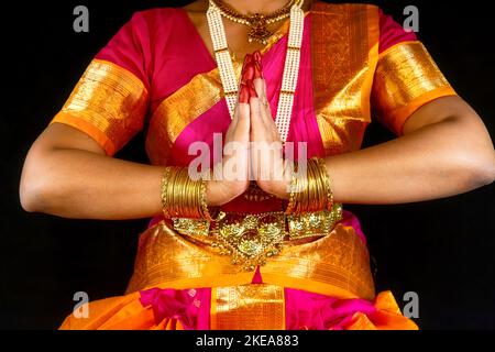 Indische Bharatanatyam-Tänzerin, die Tanzmudra oder Gesten in traditionellen Kostümen auf dunklem Hintergrund vorführt. Stockfoto