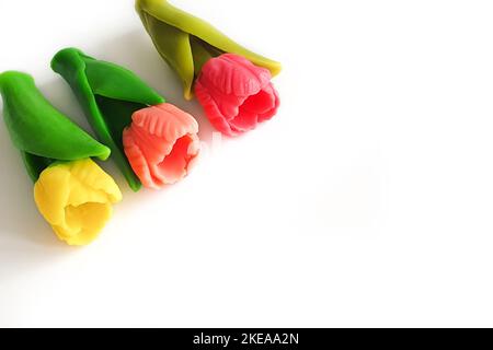 Drei rosa, rote und gelbe Tulpen aus Seife isoliert auf weißem Hintergrund. Platz auf der rechten Seite kopieren. Stockfoto