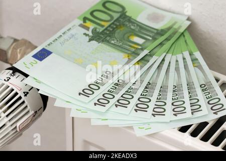 Auf dem Heizkörper liegen 100-Euro-Banknoten. Ein Symbol für steigende Heizkosten. Geld, um die Rechnungen zu bezahlen. Stockfoto