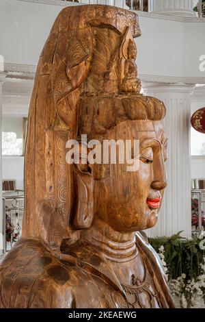 Der Tempel der Barmherzigkeit (Guanyin) in Chiang Rai, Thailand, liegt auf einem Berg und hat im Haupttempelgebäude eine Reihe von weiblichen Buddha-Figuren aus Holz. Stockfoto