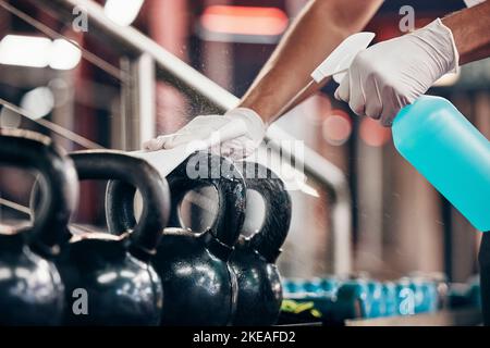 Kettlebell, Reinigungsservice und Händereinigung im Fitnessstudio mit Flüssigseife in Sprühflasche mit Tuch in Handschuhen. Reinigungstücher oder Reinigungstücher verschmutzt Stockfoto