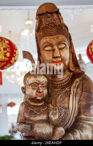 Der Tempel der Barmherzigkeit (Guanyin) in Chiang Rai, Thailand, liegt auf einem Berg und hat im Haupttempelgebäude eine Reihe von weiblichen Buddha-Figuren aus Holz. Stockfoto